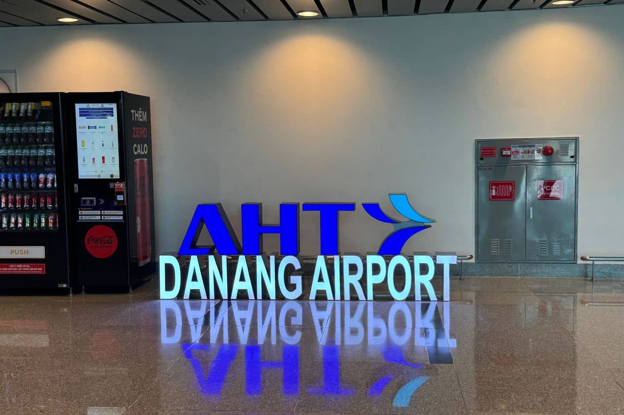 Da Nang Airport Entrance Sign and Amenities Illuminated Da Nang Airport sign next to vending machines and fire safety equipment in a modern terminal setting