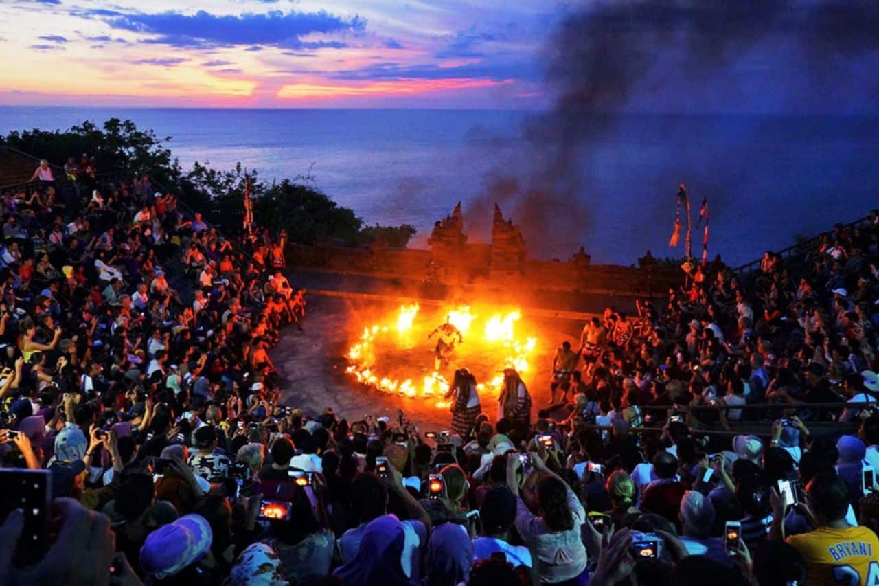 Kecak Fire Dance at Uluwatu Temple During Sunset in Bali Spectators watching the famous Kecak Fire Dance at Uluwatu Temple with ocean views at sunset.