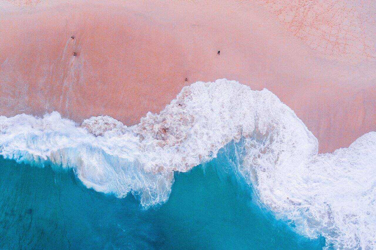 Aerial View of the Pink Beach in Komodo Overhead shot of pink sand beach and clear turquoise waves at Komodo Island.