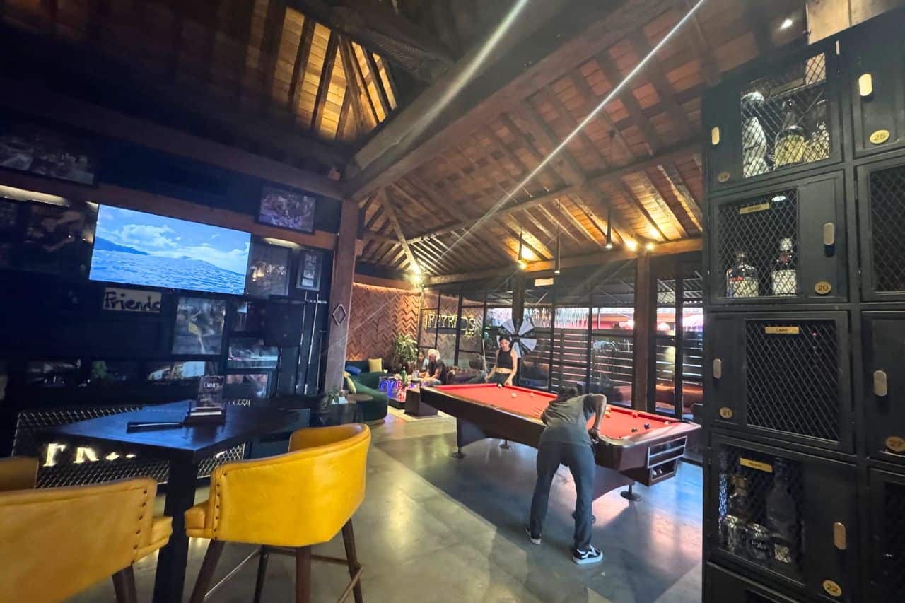 People playing pool at Friends Bar in Canggu with cozy seating and rustic decor