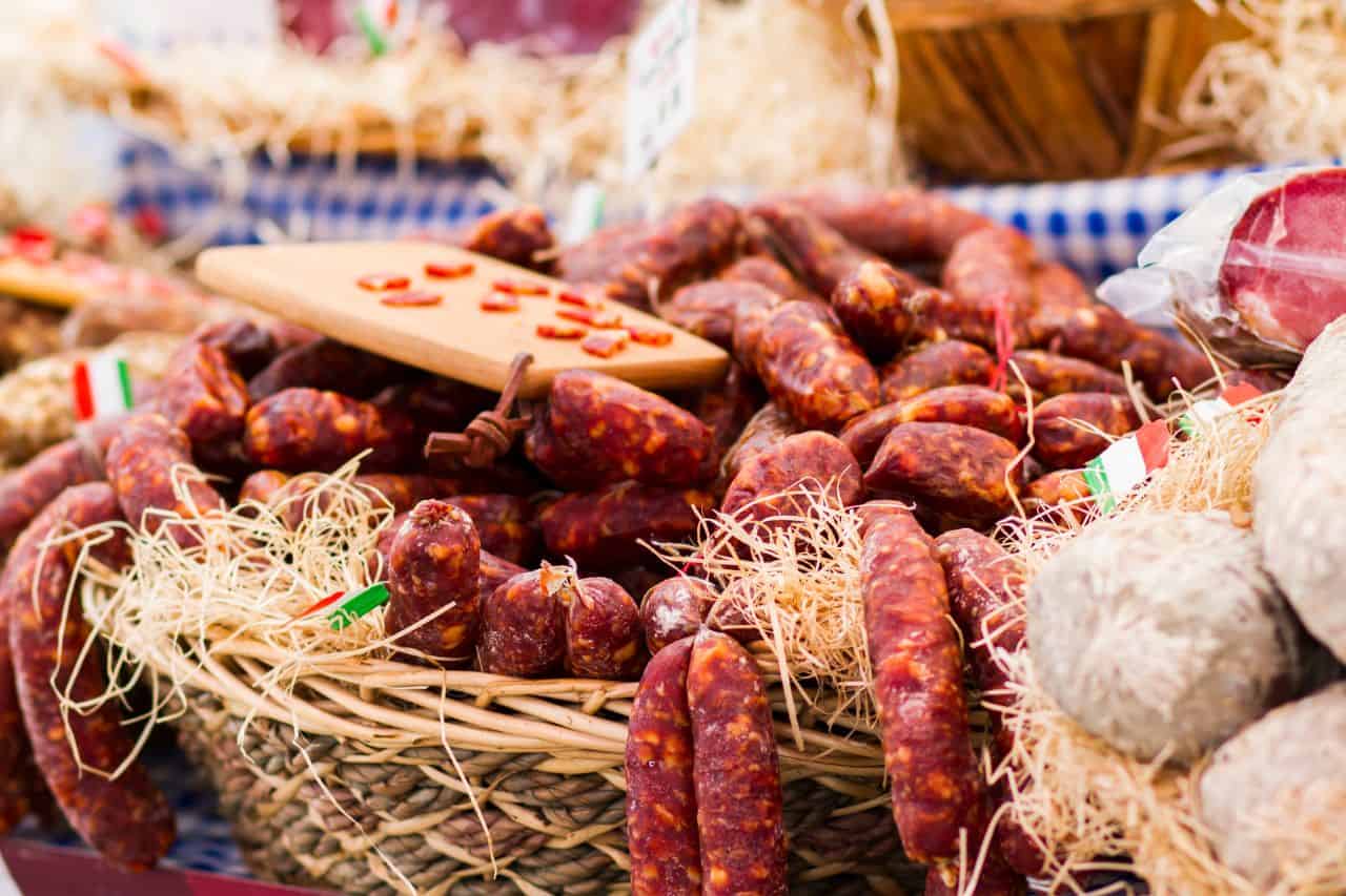 Italian Sausages for Sale - Little Italy NYC Specialty Foods Wicker basket filled with spicy Italian sausages and dried meats, showcasing authentic deli offerings in Little Italy NYC