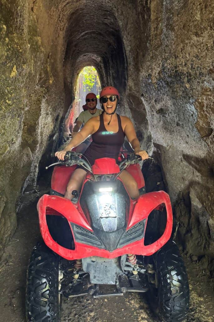 Tourists riding red ATVs through a narrow jungle tunnel during an adventure tour in Ubud Bali