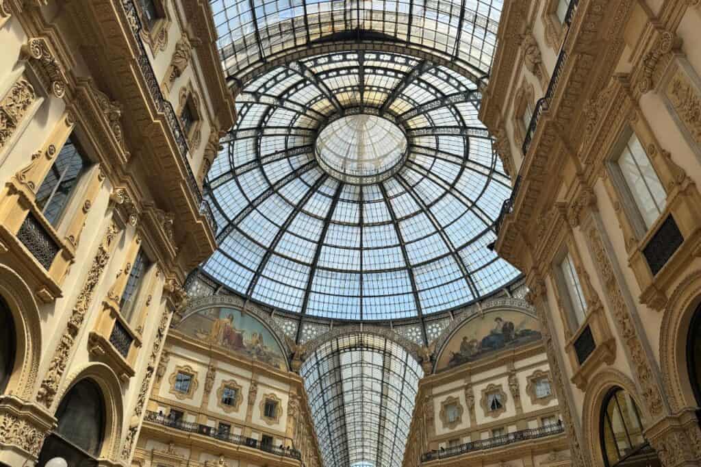Ornate glass dome ceiling with historic architecture inside Galleria Vittorio Emanuele II shopping arcade in Milan, Italy