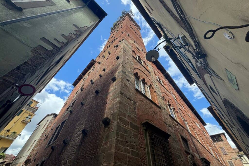 Historic stone exterior of Guinigi Tower topped with ancient oak trees in Lucca Italy