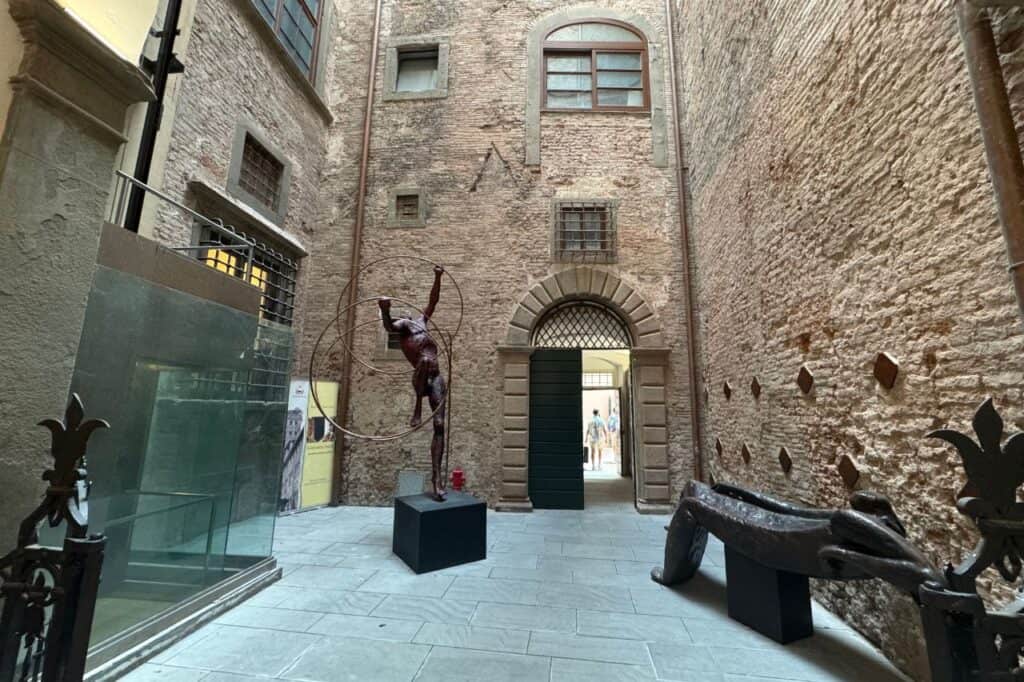 Inside Guinigi Tower in Lucca Italy, showing brick walls and a black marble statue illuminated by soft light