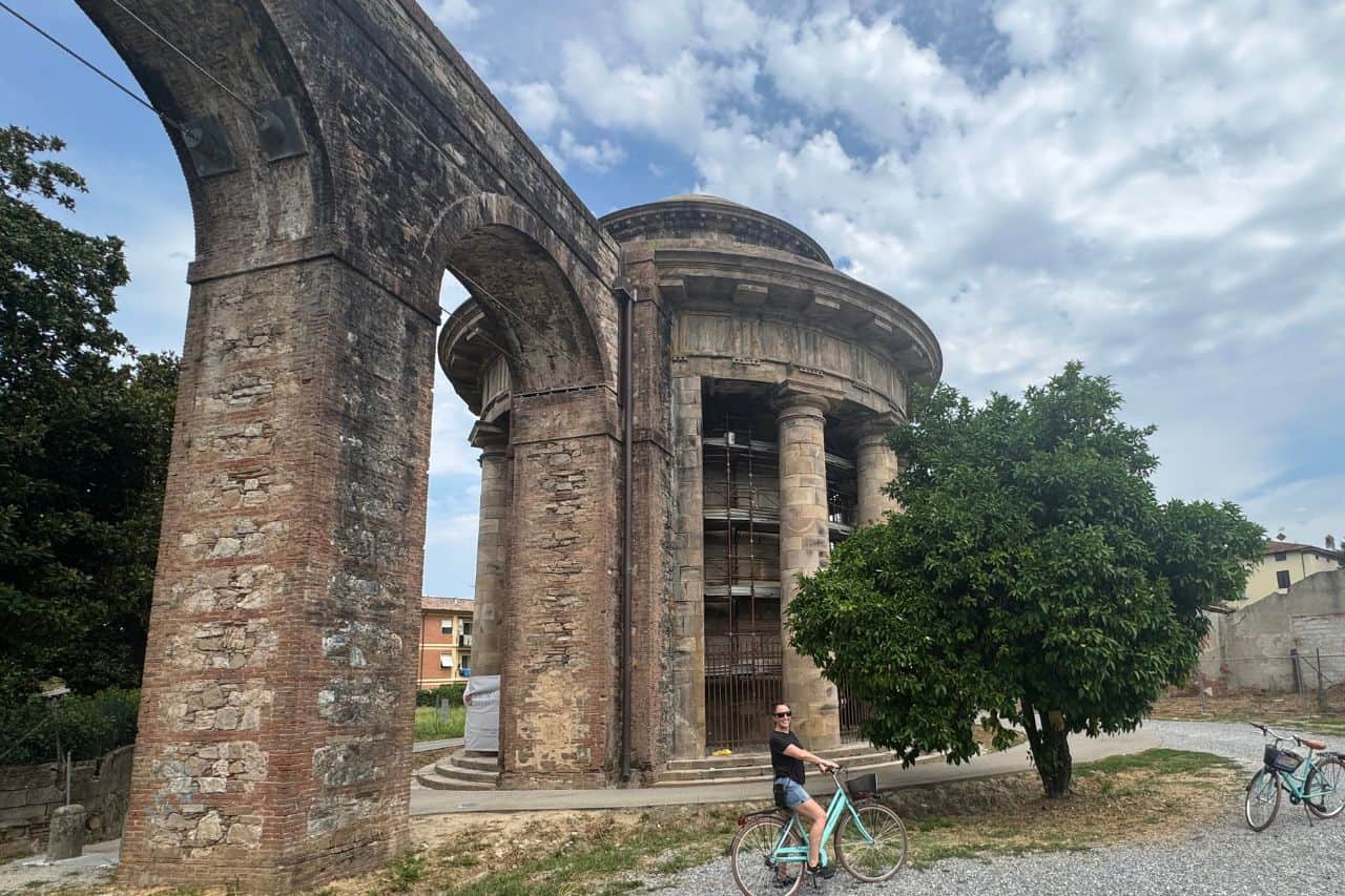 Woman riding a bike in front of the Nottolini Acqueduct in Lucca Italy