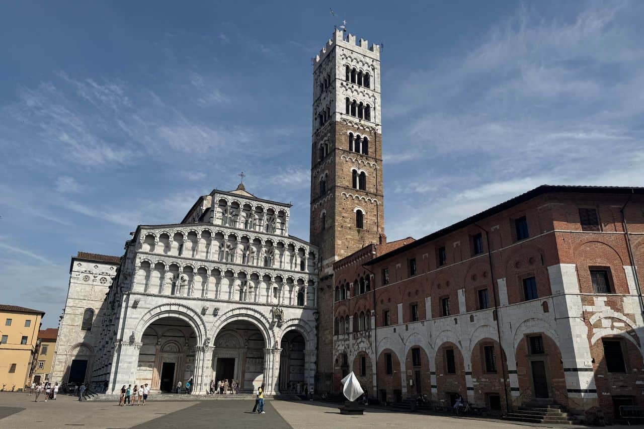 Tower and church exterior set against a blue sky in the historic center of Lucca Italy