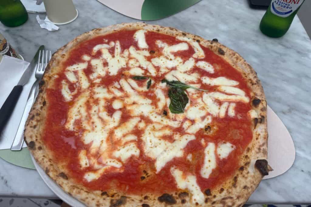 Hand placed over a Neapolitan Margherita pizza to show its large size, Naples Italy