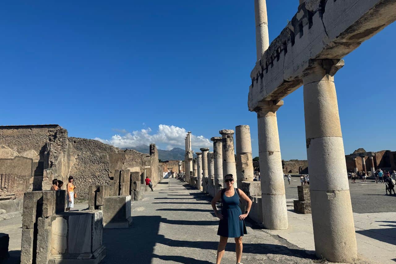 Person standing among ancient columns at the archaeological site of Pompeii, Italy