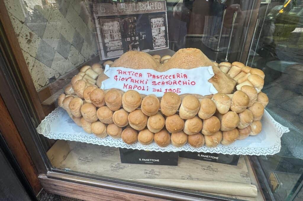 Stacked Vesuvio-shaped pastries arranged to resemble Mount Vesuvius, flaky layers and powdered sugar on a bakery display in Naples, Italy